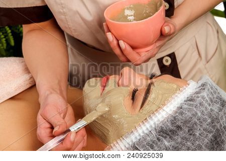Collagen face mask. Facial skin treatment. Face of woman of elderly woman 50-60 years old receiving cosmetic procedure in beauty salon close up. Cream from age spots.