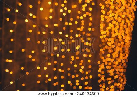 Many Blurred Small Electric Bulbs On A Wall. Yellow Blurred Lights. Wall Of Christmas Lights