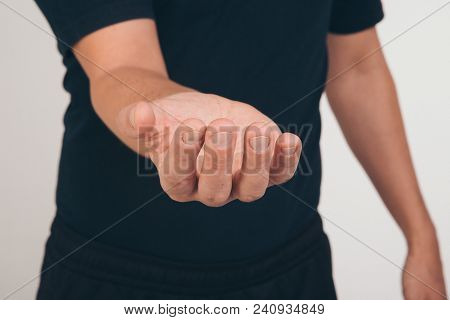 A Man In A Black T-shirt Holds His Hands In Front Of Him Palm Up