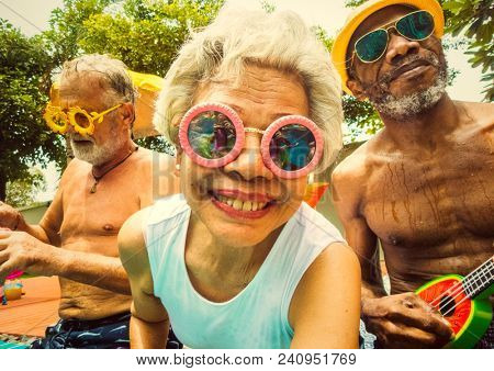 Cool seniors acting youtful by a swimming pool