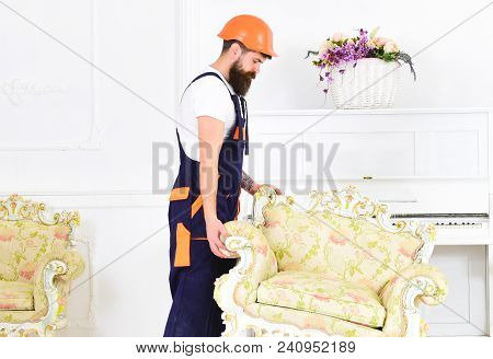 Relocating Concept. Courier Delivers Furniture In Case Of Move Out, Relocation. Loader Moves Armchai