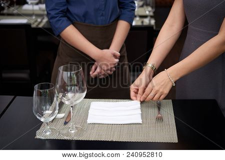 Cafe Owner Explaining Waitress How To Fold Napkins