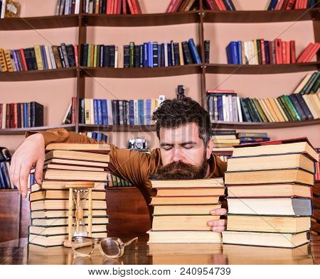 Man On Sleeping Face Lay Between Piles Of Books, Fall Asleep While Studying In Library, Bookshelves 