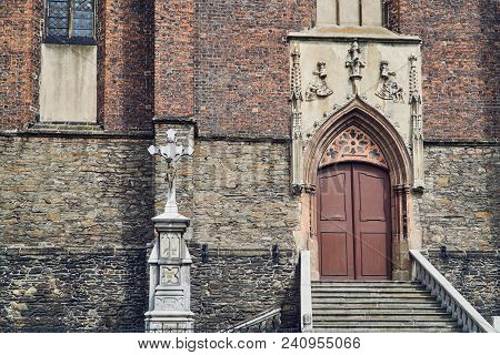 Cross And Facade Of A Medieval Defensive Church In The Gothic Style In Paczkow