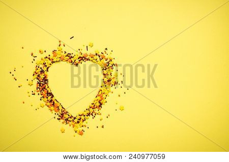 Nonpareil In Shape Of A Heart On Yellow Background. Top View