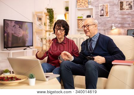 Elderly Old Couple Using Modern Laptop To Chat With Their Grandson