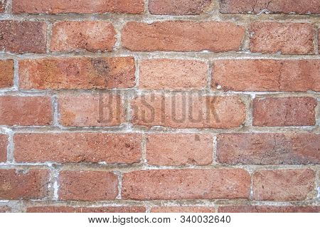 The Red Brick Wall Is Short And Long, Is An Old Brick That Has Decayed And Has White Cement Between 