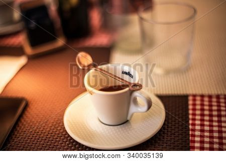 Trieste, Italy - September 2019: Lavazza Espresso Cup With Spoon And Cookie On A Table On A Warm Sum