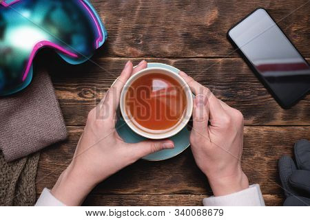 Woman Snowboarder Is Drinking A Hot Cup Of Tea On Mountain Resort Cafe.