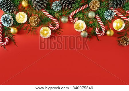 New Year Composition Made Of Christmas Balls, Cones And Striped Hard Candies On Red Background. Flat