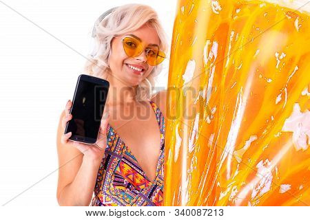 Sweet Attractive Blonde Girl In A Sexy Swimsuit In Sunglasses Holds A Phone With Mockup With A Swimm