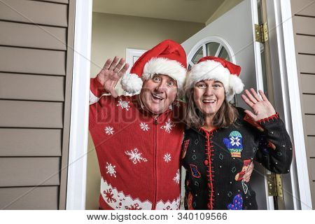 Annoying inlaws wearing santa hats welcoming family on the holiday