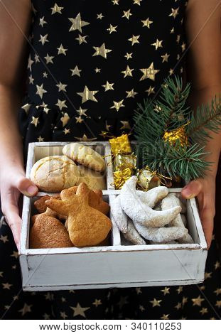 Assorted Christmas Cookies And Christmas Decorations In A Wooden Box In The Hands Of A Girl.