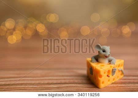 A Toy Mouse Sits In Cheese On A Wooden Starry Background, A Symbol Of 2020.
