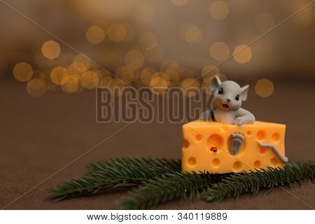 A Toy Mouse Sits In Cheese On A Wooden Starry Background With A Sprig Of Spruce And Christmas Balls.