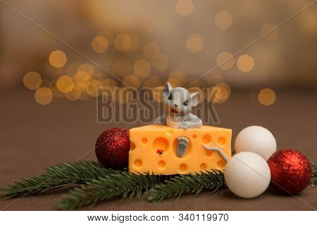 A Toy Mouse Sits In Cheese On A Wooden Starry Background With A Sprig Of Spruce And Christmas Balls.