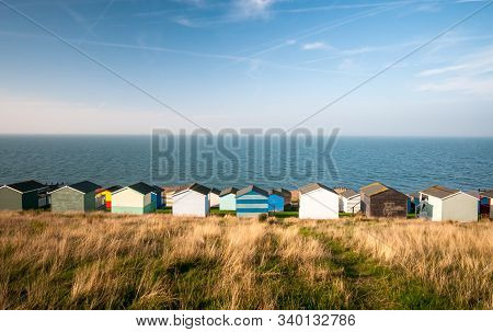 Colourful Holiday Wooden Beach Huts Facing The Calm Atlantic Sea Agains A Blue Cloudy Sky.  Whitstab