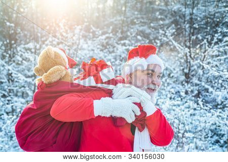 Santa Claus Coming To The Winter Forest With A Bag Of Gifts On Snow Landscape. Merry Christmas And H