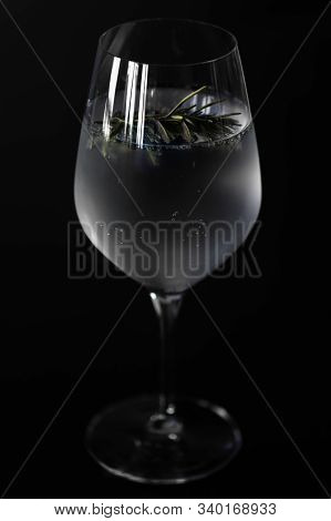 Closeup Of A Wine Glass With Ice Cold Gin Tonic With A Twig Of Rosemary For The Flavor, Isolated Bef