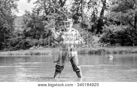 Fisherman Alone Stand In River Water. Man Senior Bearded Fisherman. Hobby Sport Activity. Pensioner 
