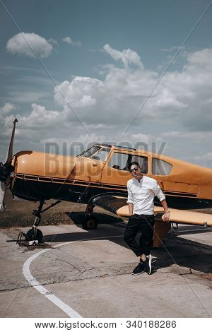 A Man Standing On The Background Of A Small Single Engine Plane.