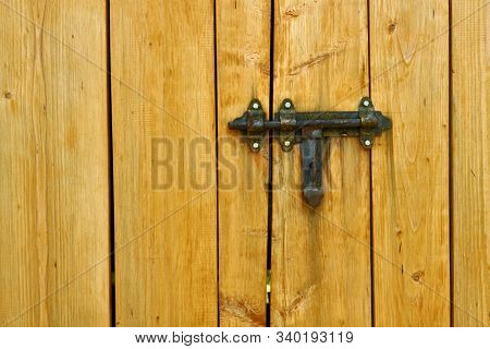 Iron latch and yellow wooden gate closeup on the ranch house for background or texture