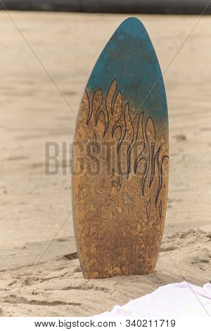 A Close Up View Of A Body, Surf Board In The Sand Next To A Beach Towl On A Warm Summers Day