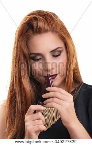 Close Up Of A Beautiful Young Redheaded Woman Holding A Perfume Bottle, Smelling The Perfume Scent W
