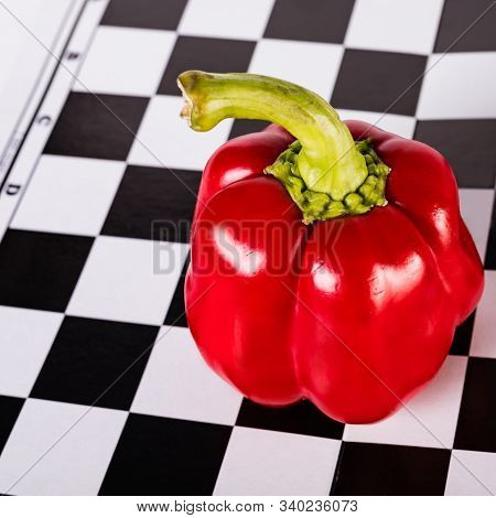Red Pepper With A Ponytail On A Chessboard. Black And White Background.