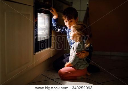 Little Toddler Girl And Cute Kid Boy Baking Muffins And Cookies In Domestic Kitchen. Two Children, S