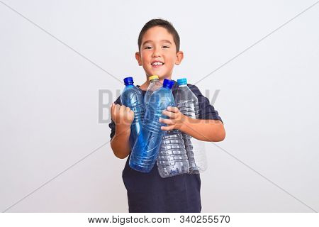 Beautiful kid boy recycling plastic bottles standing over isolated white background screaming proud and celebrating victory and success very excited, cheering emotion