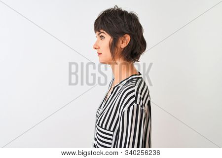 Young beautiful woman wearing striped shirt standing over isolated white background looking to side, relax profile pose with natural face with confident smile.