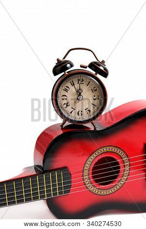 Children's Six-string Guitar And Old Retro Alarm Clock On White Background.