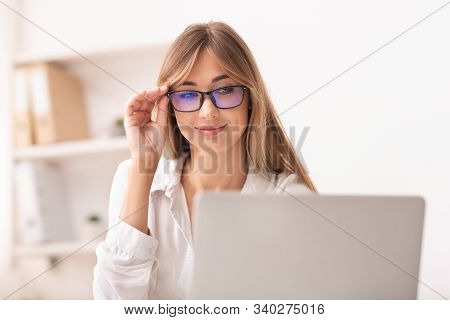 Computer Eyeglasses. Woman Using Laptop In Eyewear Working In Modern Office. Selective Focus