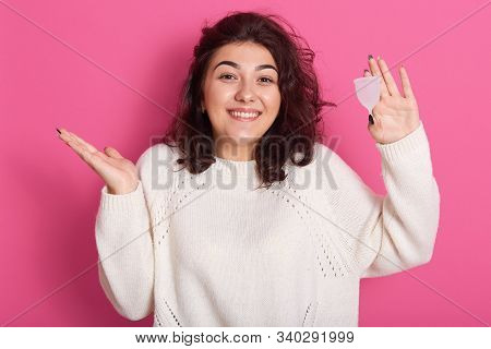 Attractive Woman Holding Menstrual Cup Standing Against Pink Background, Squeesing Her Shoulders And