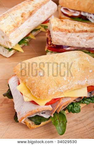 Gruppe von Ciabatta und Baguette Brötchen gefüllt mit Fleisch, Käse und Gemüse auf einem hölzernen tabl