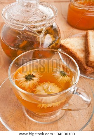 vaso con té verde de crisantemo, tostadas, mermelada y tetera