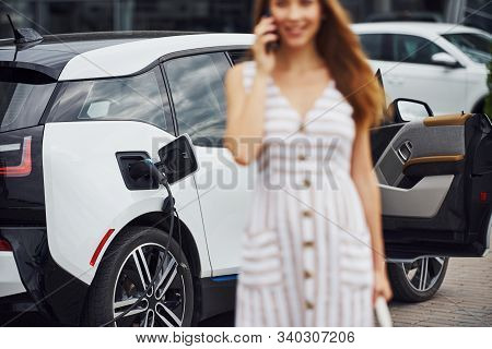 Image Focus Technique. With Phone. Woman On The Electric Cars Charge Station At Daytime. Brand New V