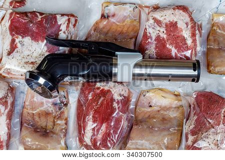 Sous Vide Immersion Circulator Cooker And The Meats Packeds On A Light Background.