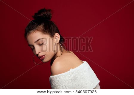 A Young Girl With A Chitina Of Delicate White Skin With Brown Hair And Round Metal Earrings Closed H