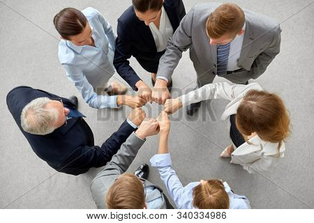 corporate, people and teamwork concept - happy business team making fist bump