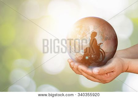 Disabled Person Silhouette On Wheelchair In Earth Was Holding In Human Hands Towards Goals On City A
