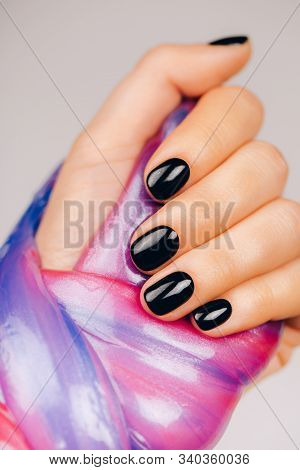 Hands With Black Manicure Holding Slime In Blue And Pink Vibrant Colors