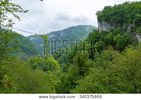 A Gorge In The Mountains With A Suspension Bridge Over It. Skybridge Suspension Bridge Over A Precip