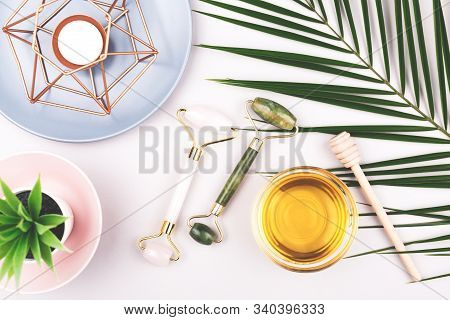Beauty Composition With Trendy Pink And Green Jade Rollers, Honey And Candle On Grey Background. Sel