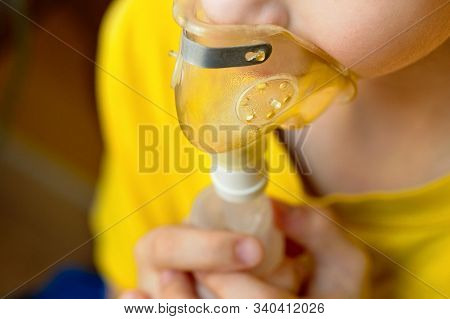 Child Makes Inhalation At Home With Nebulizer On Out Of Focus Background. Example Of Combating Respi