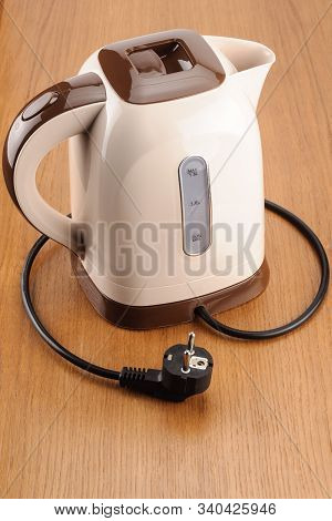 Beige And Brown Color Plastic Cordless Electrical Kettle On The Wood Background  With Base Unit