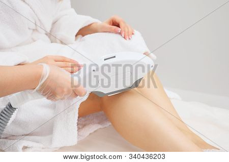 Nurse Hands In Rubber Gloves Slide Laser Head On Gelled Leg In Medical Center Making Bright Light Sp