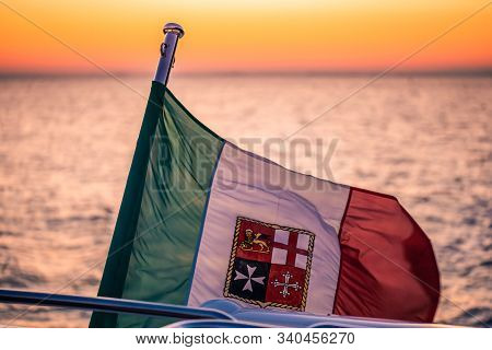 Italian Flag Blowing In The Wind While Driving A Boat At A Beautiful Sunset In Trieste, Italy.