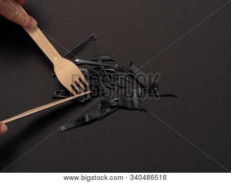 Concept Against Plastic. Cut Pieces Of Plastic Disposable Equipment Into Wooden Cutlery On Black Bac